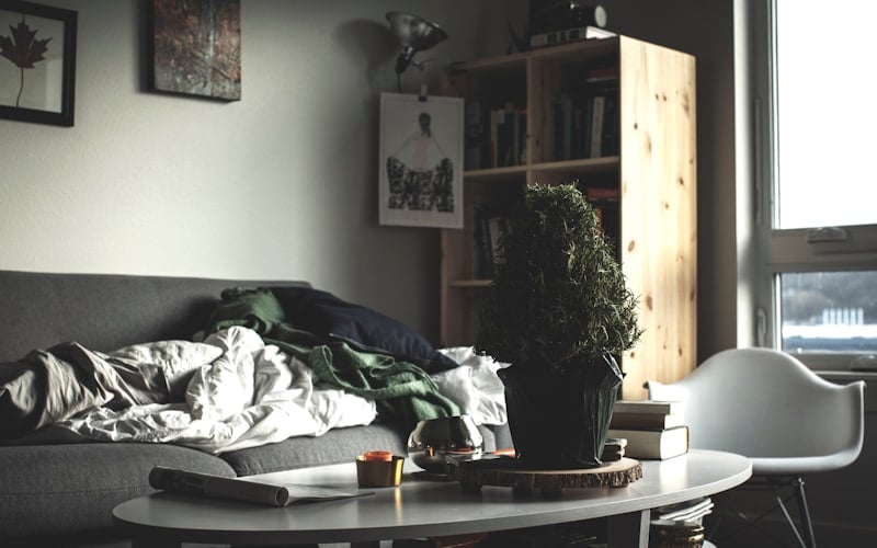 A cluttered Santa Barbara living room with clothing piled on the couch, a clear sign it's time to book a junk removal crew